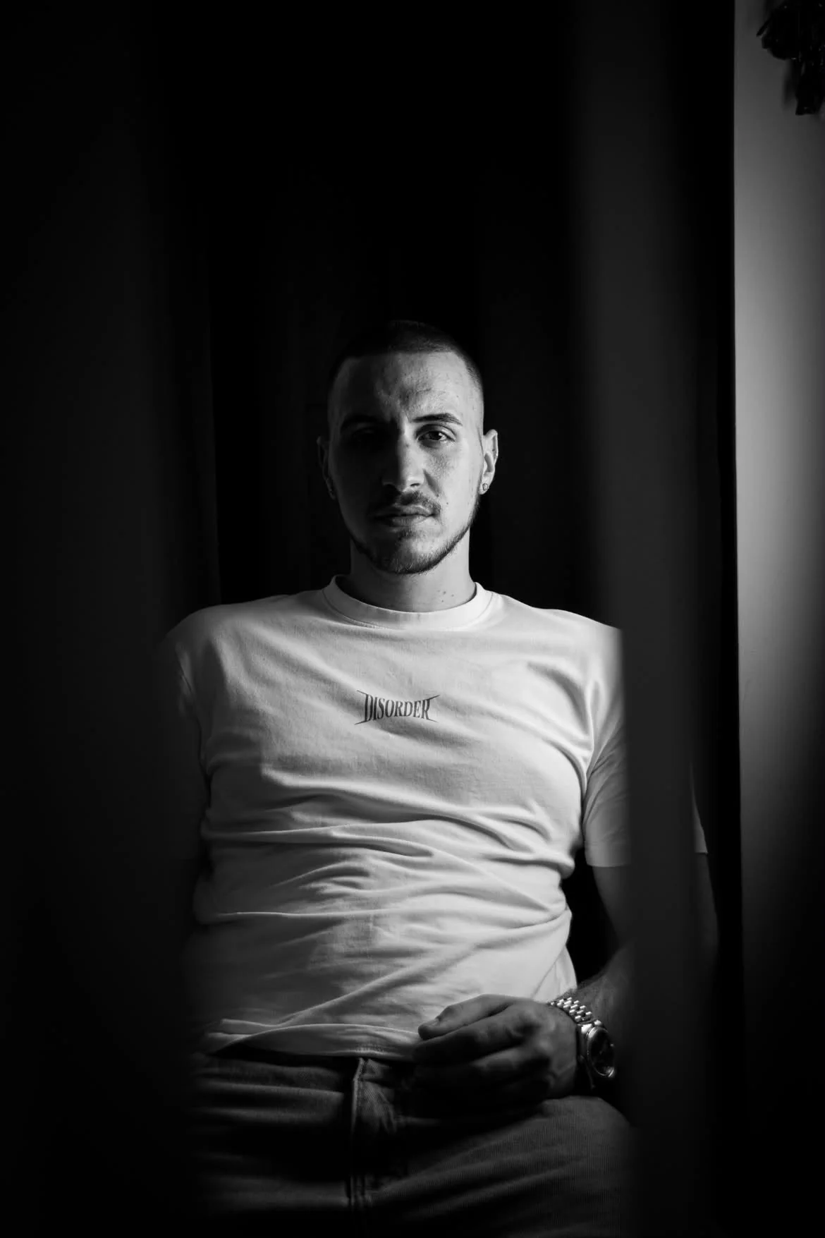 Schwarzweiß-Portrait: junger Mann im weißen T-Shirt im Fensterlicht